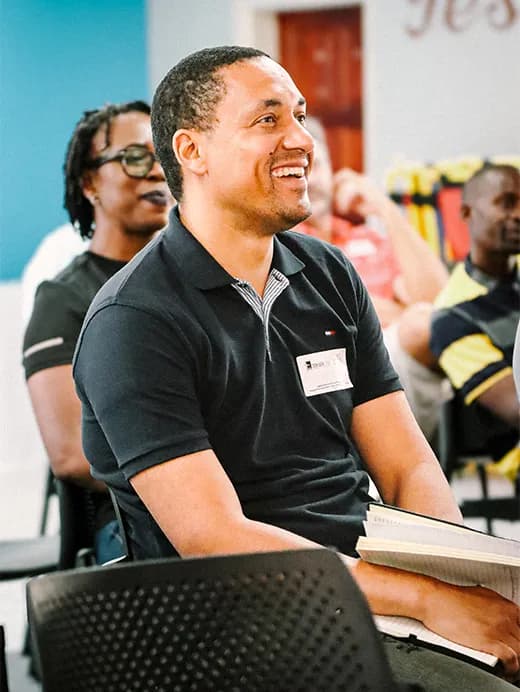 A man sitting in a chair indoors, with a big smile.